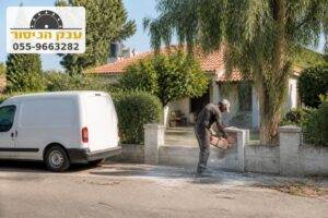 ניסור פתח בגדר בטון נמוכה מול בית פרטי עם גג רעפים וחצר ירוקה